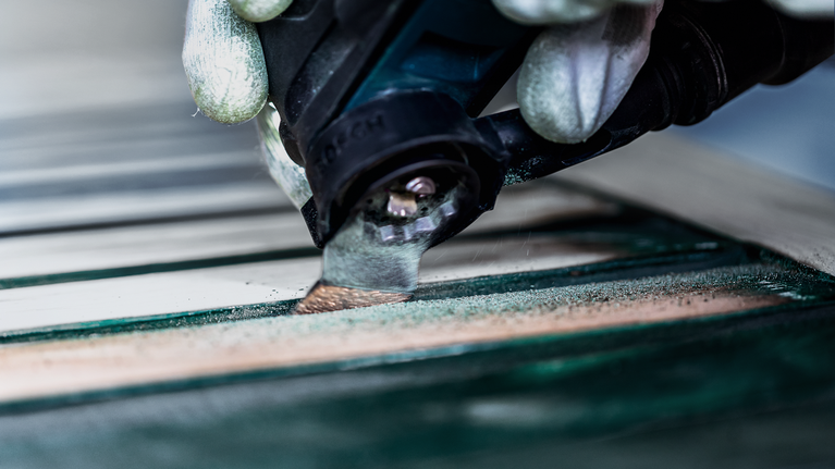 配戴安全設備的人員使用電動工具打磨木質表面。