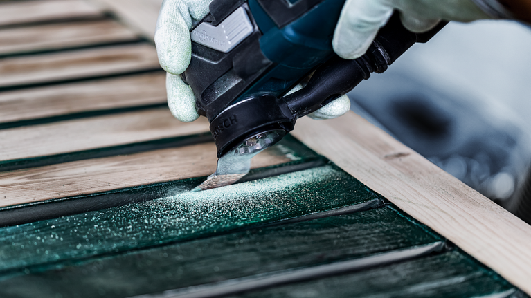 配戴安全設備的人員使用電動工具打磨木板條。