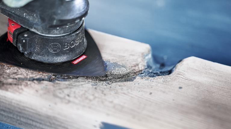 使用振盪多工具打磨和塑造一塊木頭。