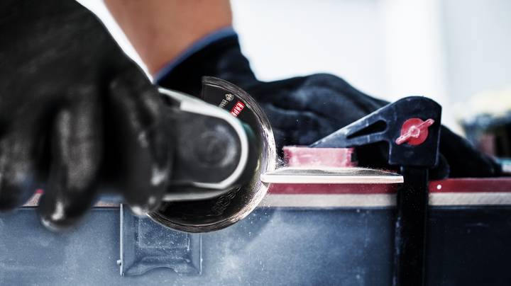 配戴安全設備的人員使用電動工具切割堅硬的表面。