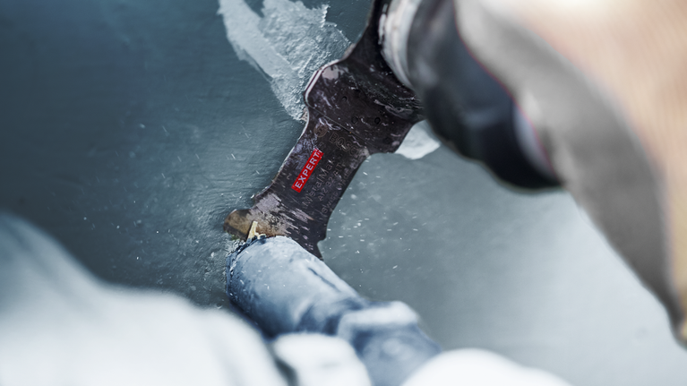 一個人用往復鋸片切割塗漆的金屬管。