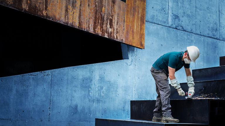 一名穿著安全裝備的人正在鑽黑色金屬樓梯。