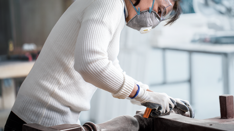 一名配戴安全設備的人員在車間打磨金屬表面。