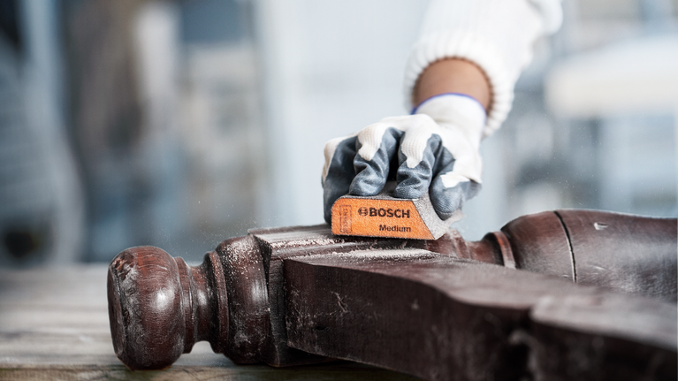 穿著安全裝備的人員正在打磨木椅扶手。