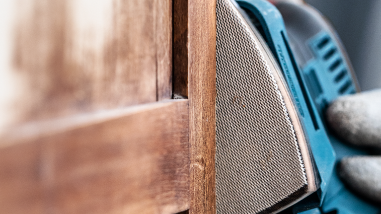 一名配戴安全設備的人員正在打磨木門的邊緣。