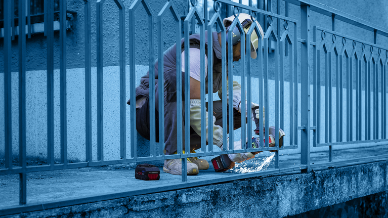 超耐久鑽石金屬切片專業款大尺寸 355 x 25.4 mm 配戴安全設備的人員使用電動工具切割金屬柵欄。