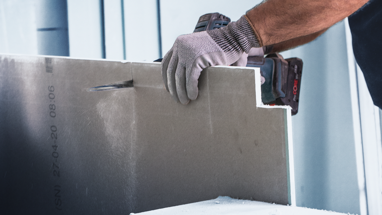 配戴安全設備的人員使用電動工具切割乾牆。