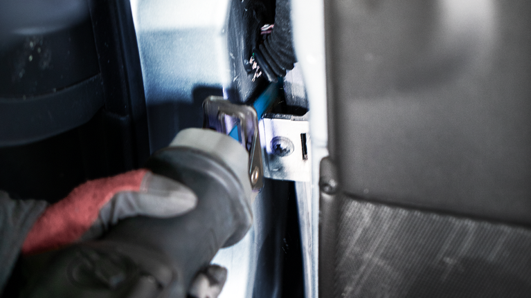 配戴安全設備的人員使用往復鋸切割車輛內部的金屬。