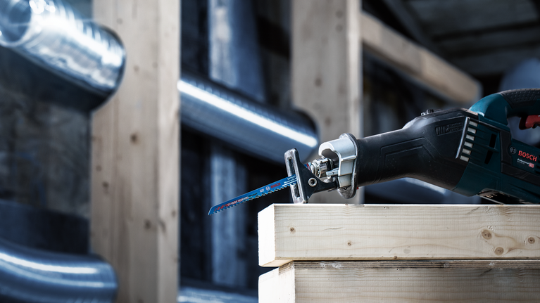 超耐久帶金屬木材專業款 S715LHM 軍刀鋸片 1 件式 往復鋸在建築環境中切割一堆木樑。