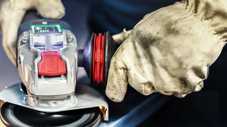 配戴安全設備的人員在金屬表面上操作角磨機。