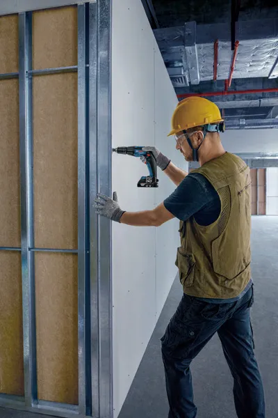 工人正在牆板上鑽孔。.