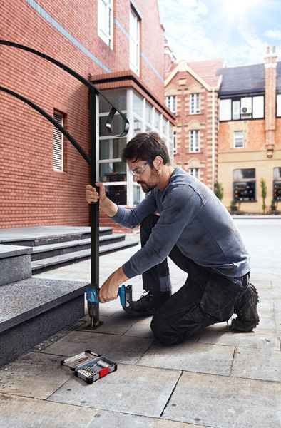 一名配戴安全設備的人員鑽入石階，安裝金屬扶手。.