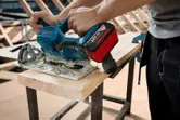 一個人使用無線圓鋸在工作台上切割木板。.