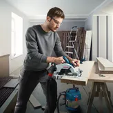 一名配戴安全設備的人員在車間使用無線圓鋸切割木材。.