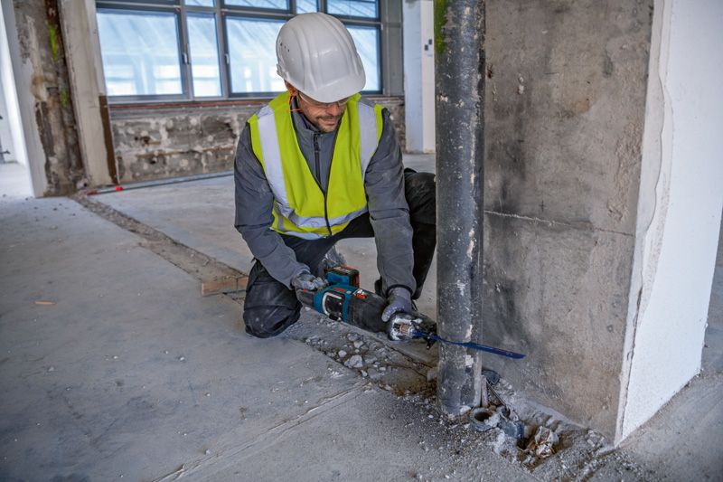 一名配戴安全設備的人員使用往復鋸切割金屬管路。.