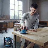 一名配戴安全設備的人員正在使用連接的軌道砂光機打磨木門。.