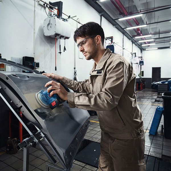 GEX 185-LI 一名配戴安全設備的人員正在用電動砂光機打磨車門。.