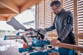 一名穿戴安全裝備的人員使用無線斜切鋸切割木材。