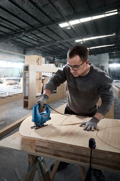 GST 680 配戴安全設備的人員使用曲線鋸在合板上切割出曲線形狀。.