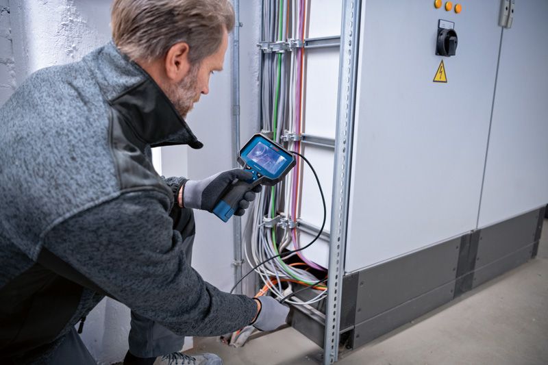 一名配戴安全裝備的人員使用內視鏡檢查電纜。