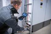 一名配戴安全設備的人員正在使用檢查攝影機檢查電線。
