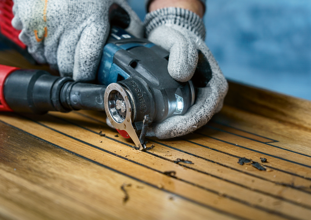 配戴安全設備的人員使用多功能工具切割木地板。