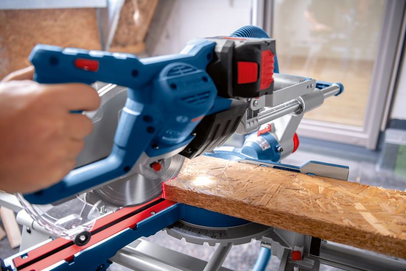 一個人使用無線斜切鋸切割木板。