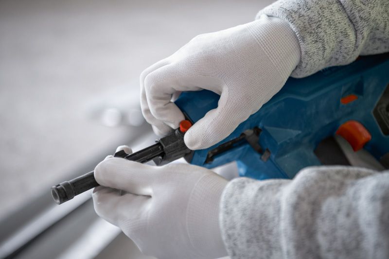 配戴安全設備的人員正在調整無線混凝土釘槍。.