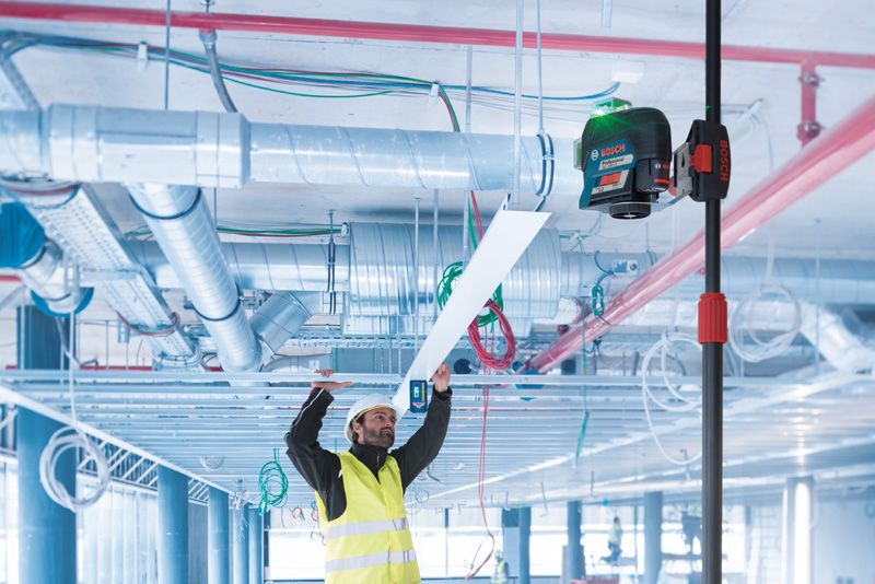 BT 350 一名配戴安全設備的人員使用伸縮桿上的雷射調平工具安裝天花板麵板。