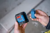 一個人拿著雷射調平工具和電池組。