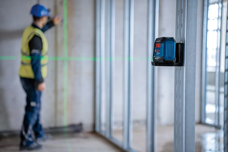 一名配戴安全設備的人員使用雷射調平工具調整牆框。