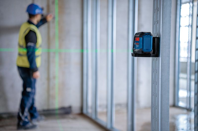 一名配戴安全設備的人員使用雷射調平工具調整牆框。