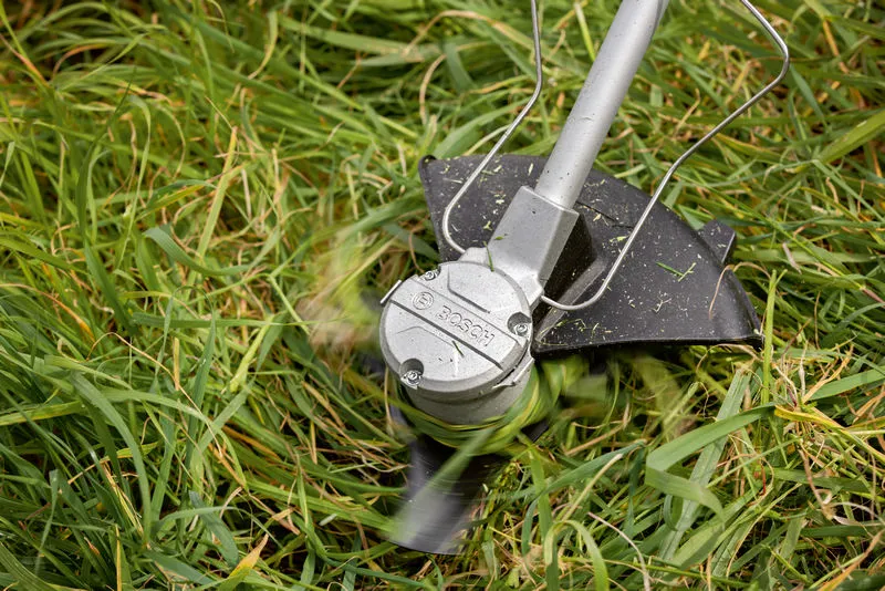 無線割草機使用旋轉刀片修剪高草。.