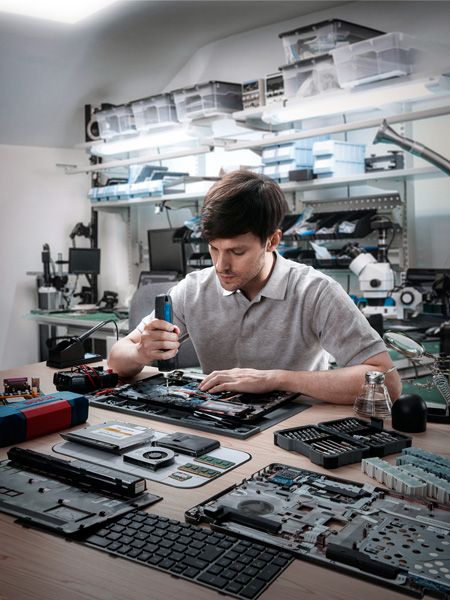 車間裡，工人正在用無線螺絲起子組裝電子設備。.