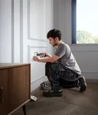 一個人用無線螺絲起子安裝電源插座蓋。.