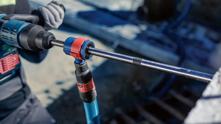 EXPERT SDS Clean max-8X 五溝鎚鑽鑽頭套裝 20 x 400 x 650 一名配戴安全設備的人員使用旋轉工具在混凝土中鑽孔。