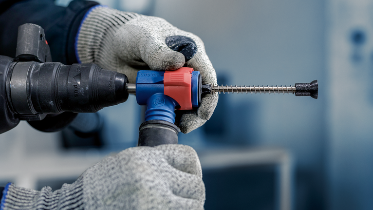 EXPERT SDS Clean plus-8X 四溝鎚鑽鑽頭 6 x 100 x 225 戴著手套的手拿著帶有鑿子鑽頭的旋轉錘鑽,穿著安全設備。.