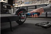 一個人使用無線螺絲起子擰緊電動滑板車輪上的螺栓。