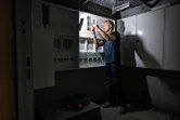 一個人在無線工作燈照亮的電氣面板上工作。