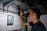 一名人員正在雜物間使用無線燈檢查電氣面板。