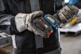 一名配戴安全設備的人員將電池組安裝到無線電動工具上。