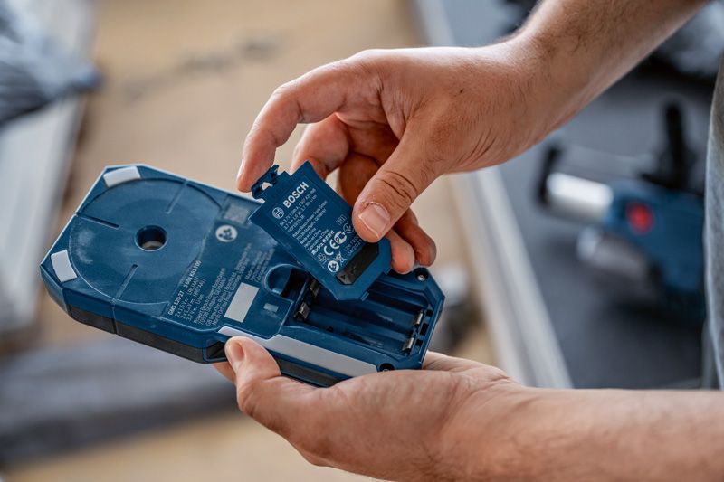 一個人將電池組插入藍色電動工具外殼。.