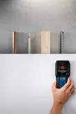 一個人使用探測器掃描牆壁以尋找金屬、木材和電線。