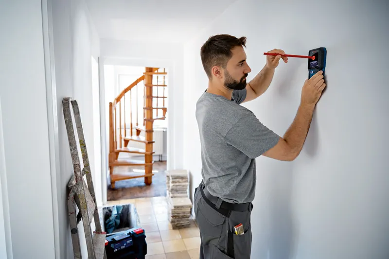 一名男子在使用探測器時用鉛筆在牆上做標記。.