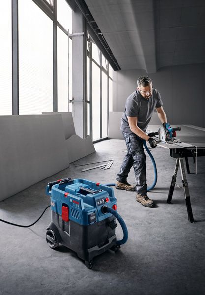 一名配戴安全設備的人員使用多用途萃取器切割支架上的木板。.