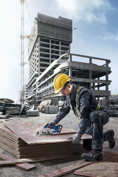 一名配戴安全設備的人員在工地切割堆疊的合板。.