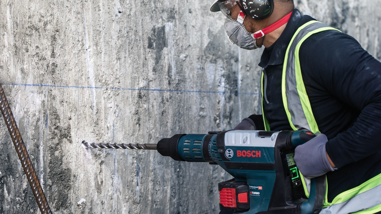 PRO SDS max-4 四溝鎚鑽鑽頭,12 x 200 x 340 mm 一名佩戴安全設備的人正在鑽入混凝土牆。