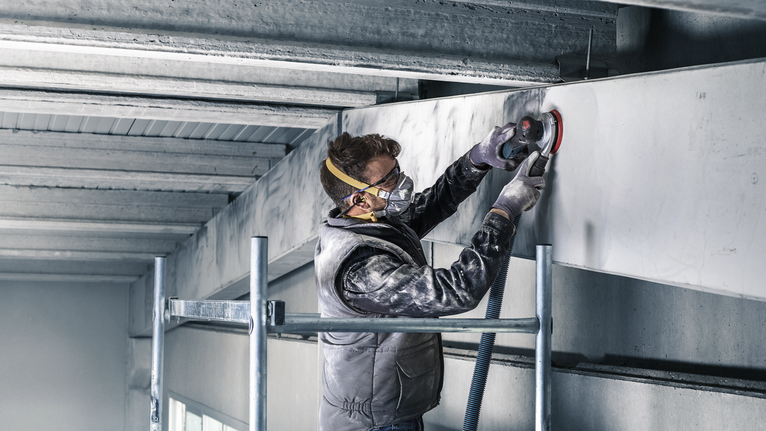 PRO F355 專業款砂磨砂輪片,125 mm,G320,5 件組 一名配戴安全設備的人員使用電動工具打磨混凝土梁。