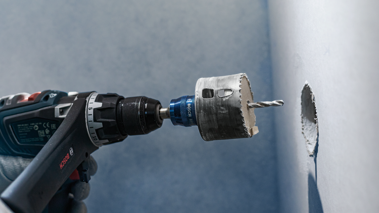 配戴安全設備的人員在牆上鑽一個圓孔。