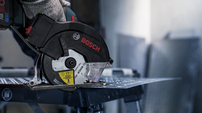 佩戴安全設備的人用圓鋸切割金屬板。